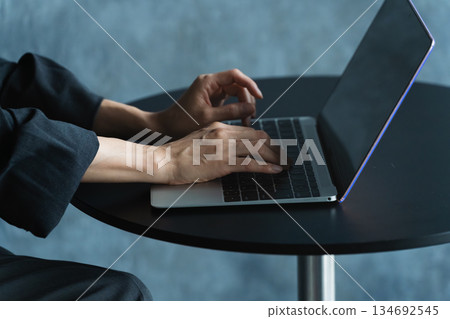 Woman using a laptop at a table Lifestyle image Woman using a laptop at a table Lifestyle image 134692545
