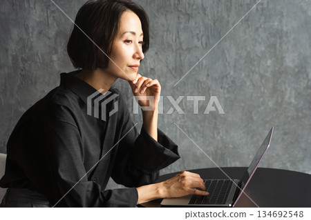 一位女士在桌旁使用筆記型電腦。 （生活照） 134692548