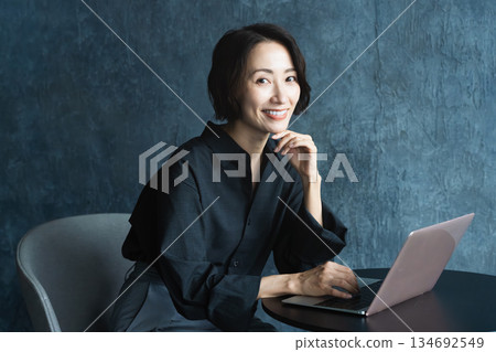 Woman using a laptop at a table Lifestyle image Woman using a laptop at a table Lifestyle image 134692549