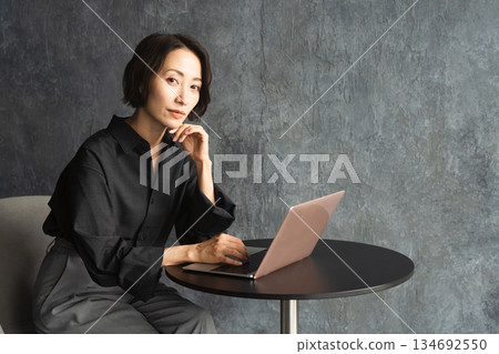 Woman using a laptop at a table Lifestyle image Woman using a laptop at a table Lifestyle image 134692550