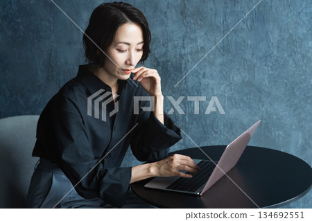 Woman using a laptop at a table Lifestyle image Woman using a laptop at a table Lifestyle image 134692551