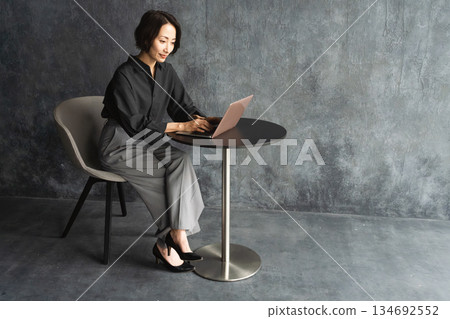 Woman using a laptop at a table Lifestyle image Woman using a laptop at a table Lifestyle image 134692552