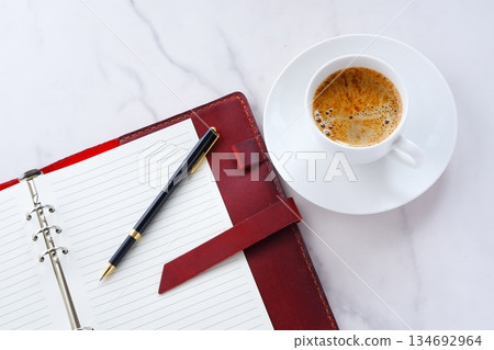 Image of a man working at his desk with a system organizer while drinking a cafe latte, a coffee with plenty of milk 134692964