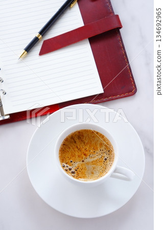 Image of a man working at his desk with a system organizer while drinking a cafe latte, a coffee with plenty of milk Image of a man working at his desk with a system organizer while drinking a cafe latte, a coffee with plenty of milk 134692965