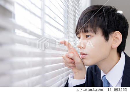 亞洲商人透過百葉窗向外張望 亞洲商人透過百葉窗向外張望 134693265