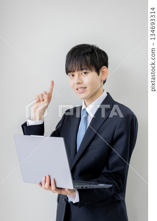 Businessman holding a laptop and pointing Businessman holding a laptop and pointing 134693314