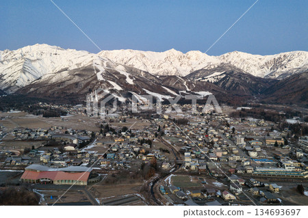 The beautiful Hakuba mountain range and the townscape of Hakuba Village before sunrise. Hakuba Village, Nagano Prefecture (aerial shot by drone) 134693697