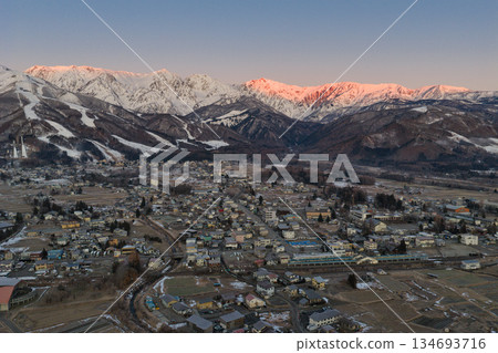 The beautiful morning glow of the Hakuba mountain range and the townscape of Hakuba Village, Nagano Prefecture (aerial shot by drone) 134693716
