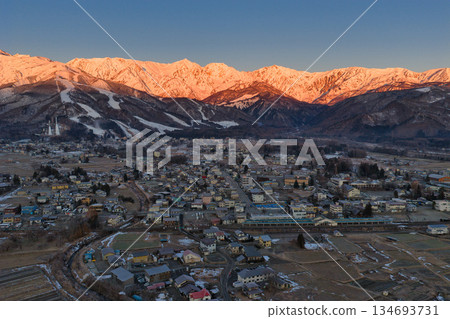 Beautiful morning glow of the Hakuba Sanzan mountains and the townscape of Hakuba Village, Nagano Prefecture (aerial shot by drone) 134693731