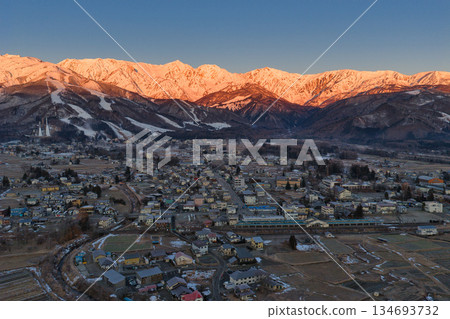 Beautiful morning glow of the Hakuba Sanzan mountains and the townscape of Hakuba Village, Nagano Prefecture (aerial shot by drone) 134693732