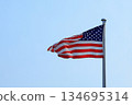 The American flag, the Stars and Stripes, flutters vigorously in the clear sky 134695314
