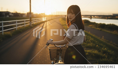 A woman pushing a bicycle on her way home at dusk 134695461
