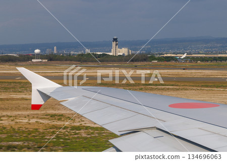 Wing of a jet taking off from Honolulu Airport, with the control tower visible in the distance Wing of a jet taking off from Honolulu Airport, with the control tower visible in the distance 134696063