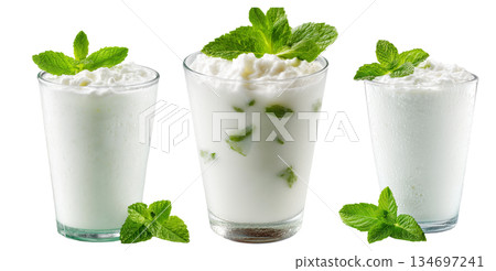 Ayran salted yogurt drink in tall glass with foamy top and mint leaf, isolated on white background, concept of healthy drink Ayran salted yogurt drink in tall glass with foamy top and mint leaf, isolated on white background, concept of healthy drink 134697241