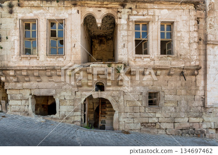 Old stone house facade with broken windows and arched entrance, Cappadocia, Turkey. 134697462