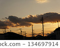 Clouds and power lines illuminated by the setting sun 134697914