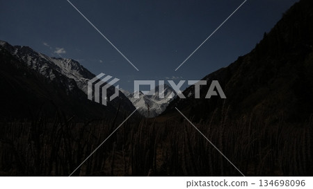 Majestic mountain landscape with snow-capped peaks and dark valley 134698096