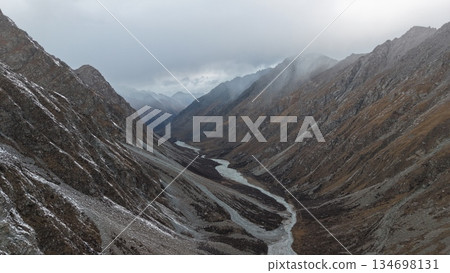Majestic mountain valley with winding river and dramatic cloud cover Majestic mountain valley with winding river and dramatic cloud cover 134698131
