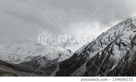 Snowy mountain landscape with dramatic clouds and winding river below Snowy mountain landscape with dramatic clouds and winding river below 134698133