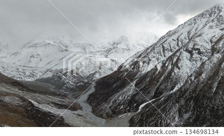 Snowy mountain landscape with river flowing through valley and clouds Snowy mountain landscape with river flowing through valley and clouds 134698134