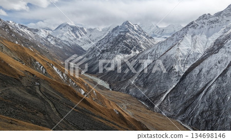 Majestic snow-capped mountains overlooking winding river valley landscape 134698146