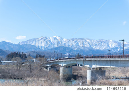 橫跨最上川和白雪皚皚的山峰的橋樑 橫跨最上川和白雪皚皚的山峰的橋樑 134698216