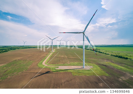 Wind turbines generate renewable energy in a wind farm located in a rural area under a clear sky during daylight hours Wind turbines generate renewable energy in a wind farm located in a rural area under a clear sky during daylight hours 134699846