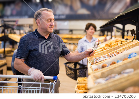 mature man choosing bread and baking in grocery section of supermarket 134700206