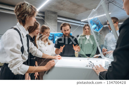 Explaining how the device works. People are in the office by the 3d printer Explaining how the device works. People are in the office by the 3d printer 134700428