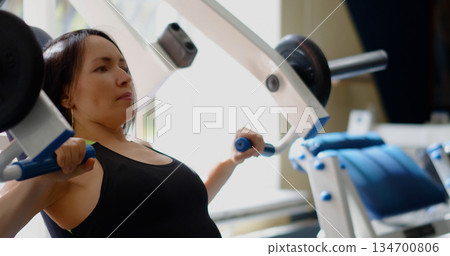 Caucasian woman in excellent physical shape during gym workout. Bench press for chest. Physical education as a norm of life to maintain health. Caucasian woman in excellent physical shape during gym workout. Bench press for chest. Physical education as a norm of life to maintain health. 134700806