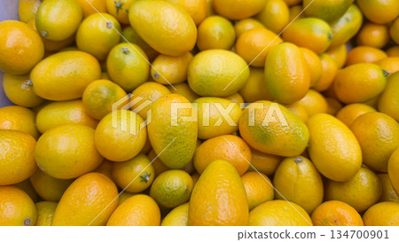 Yellow oval kumquats in large boxes on store shelves. Exotic fruit for sale. Yellow oval kumquats in large boxes on store shelves. Exotic fruit for sale. 134700901
