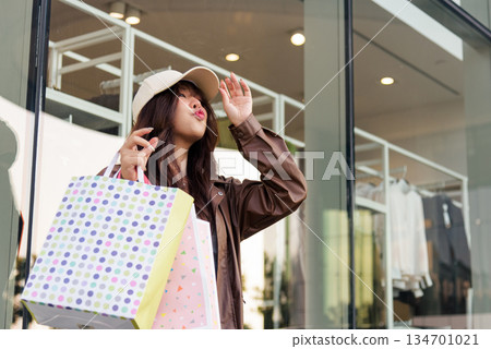 Asian woman shopping, holding fashion bags at mall, enjoying lifestyle among people, posing for black friday shop deals and big sales 134701021