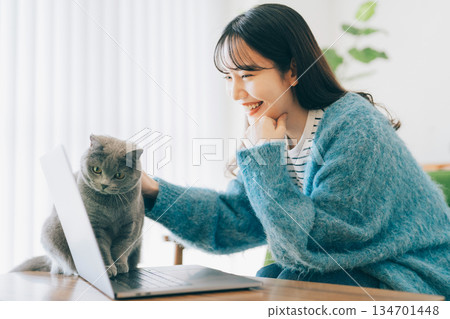 一隻貓和一位女士一起看著電腦。 134701448