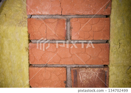Exposed red brick with yellow plaster, rough mortar lines and paint flakes, weathered edge, architectural texture ideal for background and renovation concept 134702499