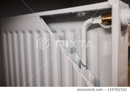 Corroded radiator with flaking paint, Closeup of aged radiator showing rust and deterioration, Surface of deteriorated radiator displaying peeling paint and rust layers 134702502