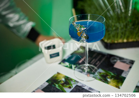 Vibrant lime cocktail presentation, Bartender displays colorful drink elegantly, Focus on bartender presenting vibrant green drink in stylish setting with soft lighting 134702506