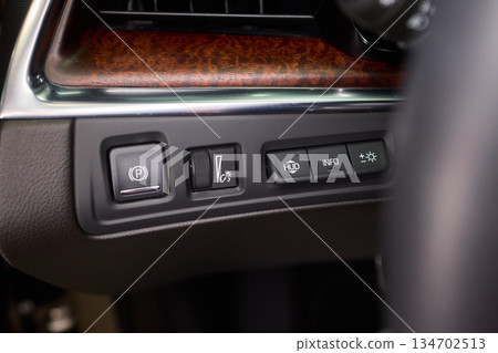Closer view of dashboard controls featuring illumination and safety icons, Detailed snapshot of vehicle dashboard with various illuminated safety and driving assistance 134702513
