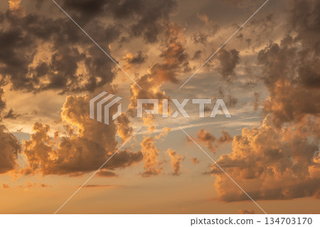 Dramatic golden clouds create a stunning sunset display over the horizon during evening hours Dramatic golden clouds create a stunning sunset display over the horizon during evening hours 134703170