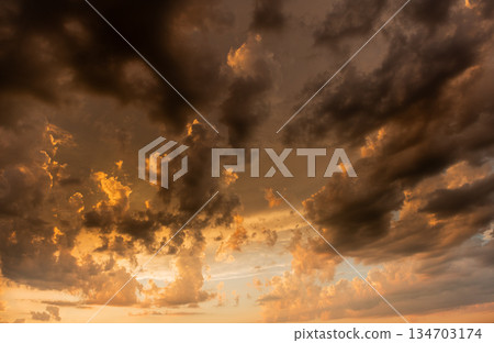 Dramatic golden clouds create a stunning sunset display over the horizon during evening hours Dramatic golden clouds create a stunning sunset display over the horizon during evening hours 134703174