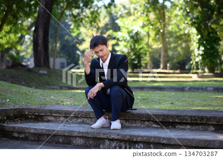 Office man stressed and sitting on outdoor steps in a green park 134703287