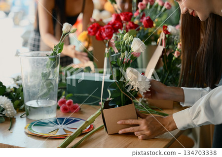 Group of people arranging colorful flowers together in a creative floral workshop 134703338