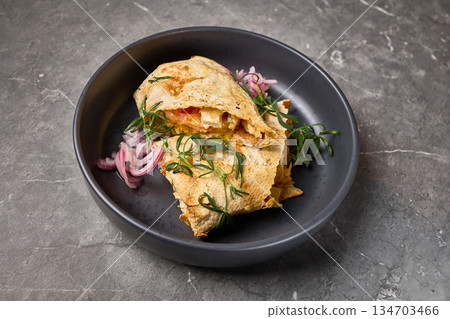 Delicious cheesy quesadilla with fresh herbs and onions served on dark plate, stone background, closeup view, Mexican food concept 134703466