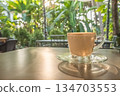 Coffee cup latte art on wooden table background with sunlight in a garden 134703553