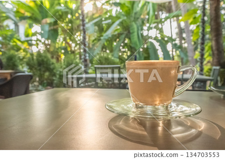 Coffee cup latte art on wooden table background with sunlight in a garden 134703553