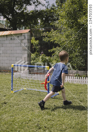 Boy running on grass in backyard playing with toy bow and arrow near soccer goal enjoying outdoor play on sunny summer day Boy running on grass in backyard playing with toy bow and arrow near soccer goal enjoying outdoor play on sunny summer day 134703593