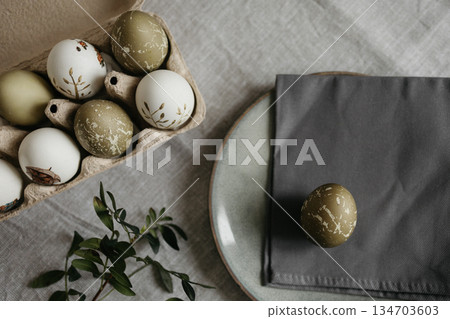 Easter holiday. Painted olive-colored eggs on a linen tablecloth. Easter decoration. 134703603