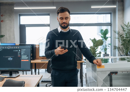 Smartphone in hand. Man is in the modern office, one person Smartphone in hand. Man is in the modern office, one person 134704447