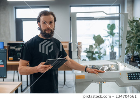 Standing, working. Man is in the office with 3d printer Standing, working. Man is in the office with 3d printer 134704561