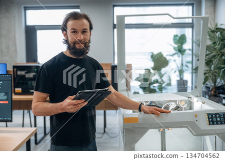 Standing, working. Man is in the office with 3d printer Standing, working. Man is in the office with 3d printer 134704562