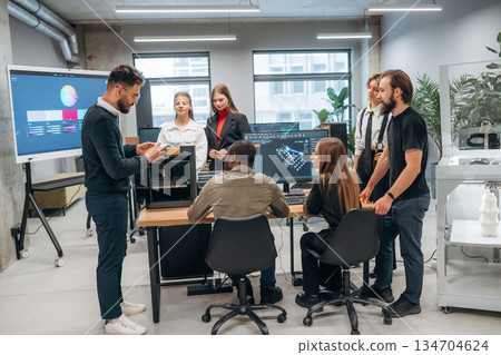 3d printer is on the table. Designer team are together in the office 3d printer is on the table. Designer team are together in the office 134704624